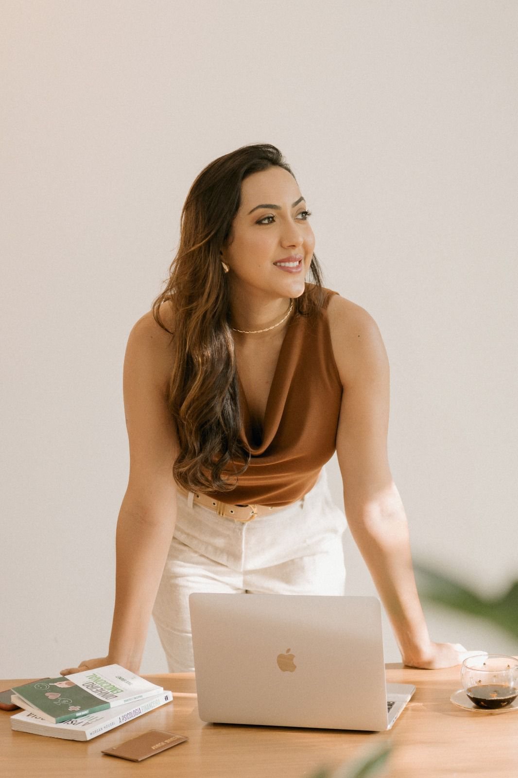 Kariny trabalhando no notebook em uma mesa clara.